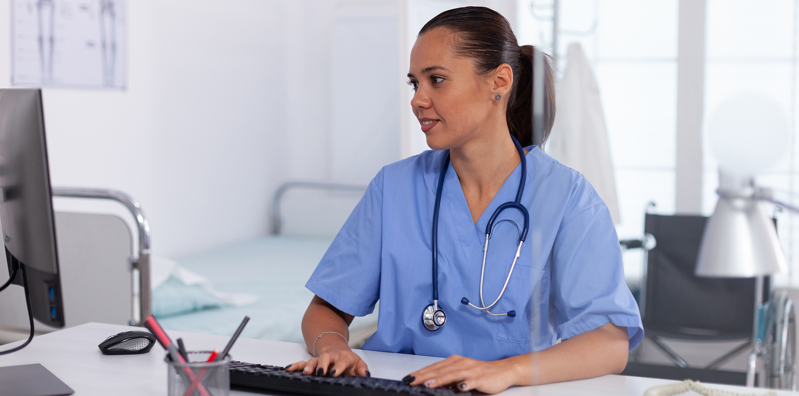 medical-practitioner-using-computer-in-hospital-office-health-care-physician-using-computer-in-modern-clinic-looking-at-monitor-medicine-profession-scrubs